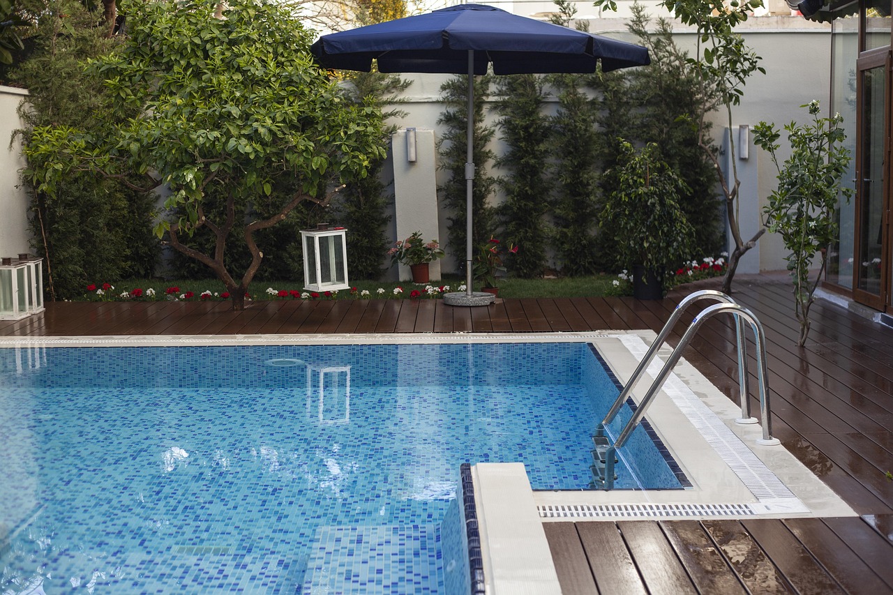 A luxury swimming pool and terrace with garden foliage.