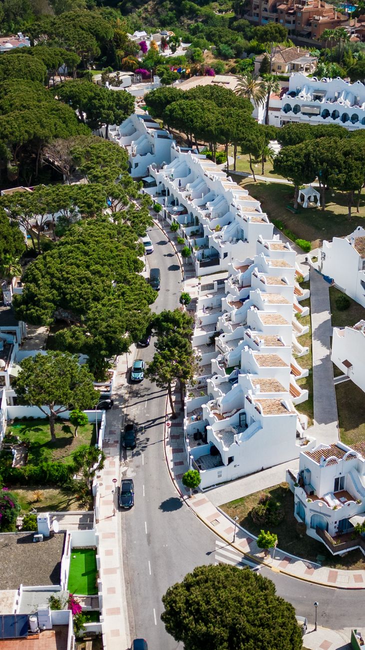 Aerial view of white townhouses and tree-lined street in Marbella