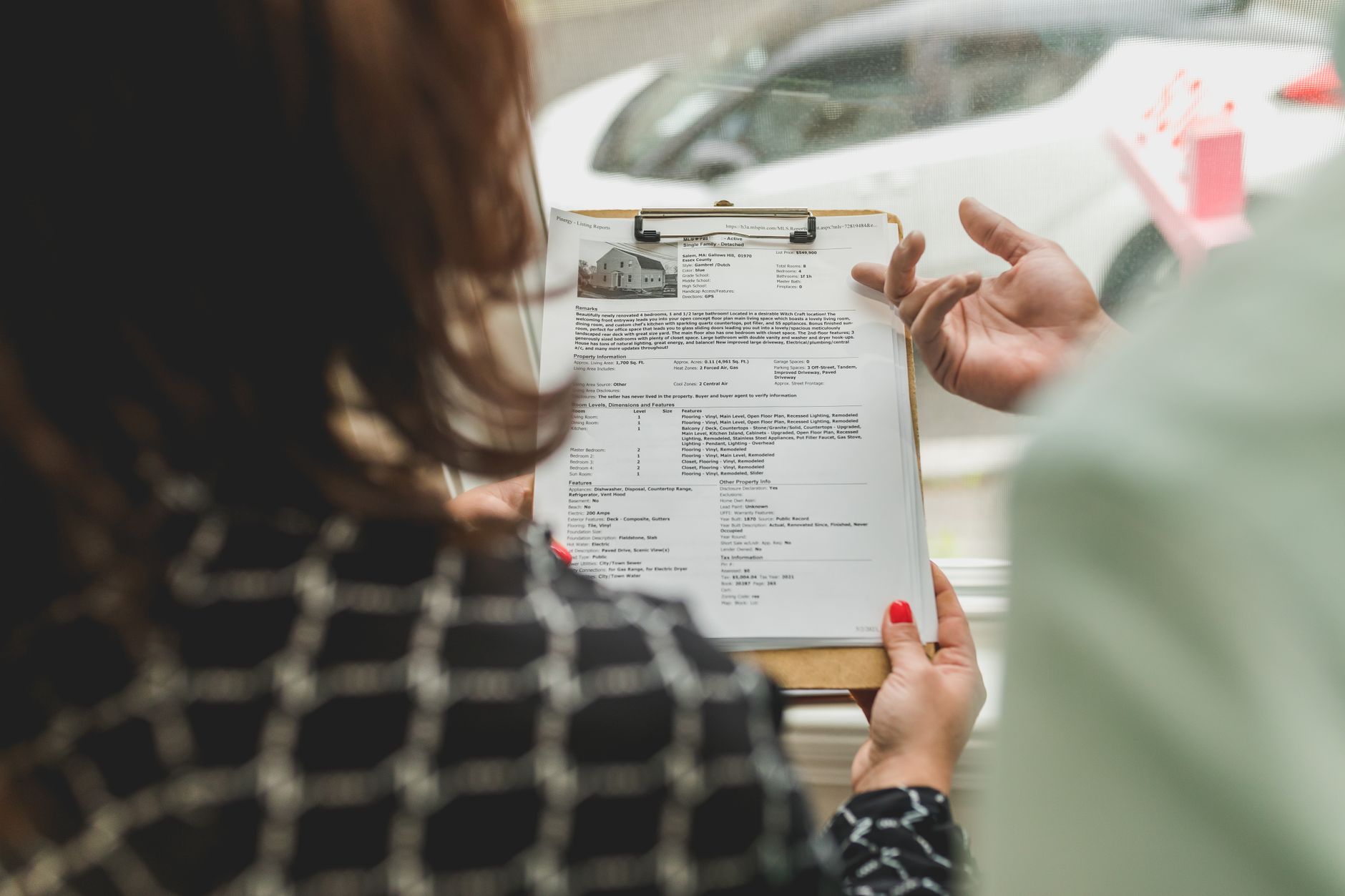Real estate agent and client reviewing property documents on a clipboard
