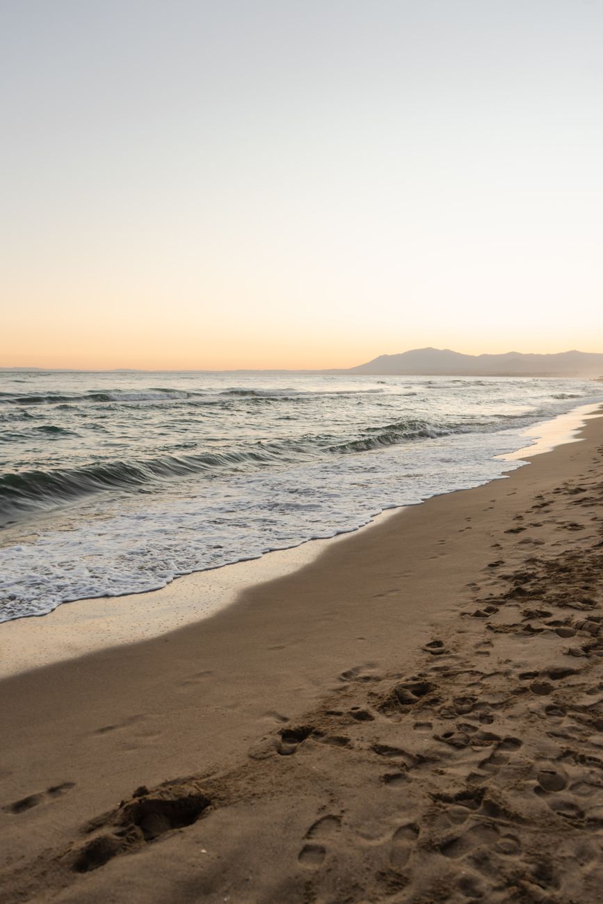 Sandy beach with gentle waves at sunrise along the coastline